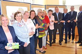 Das Bild zeigt elf Menschen die sich gegenseitig an der Hand halten. 