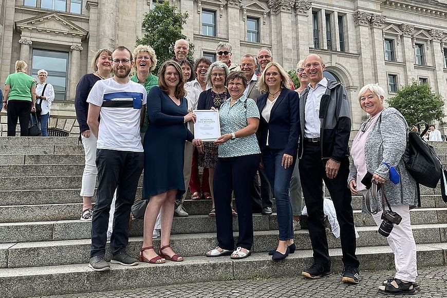 Gruppenfoto auf einer Treppe, zwei Personen halten ein Papier hoch