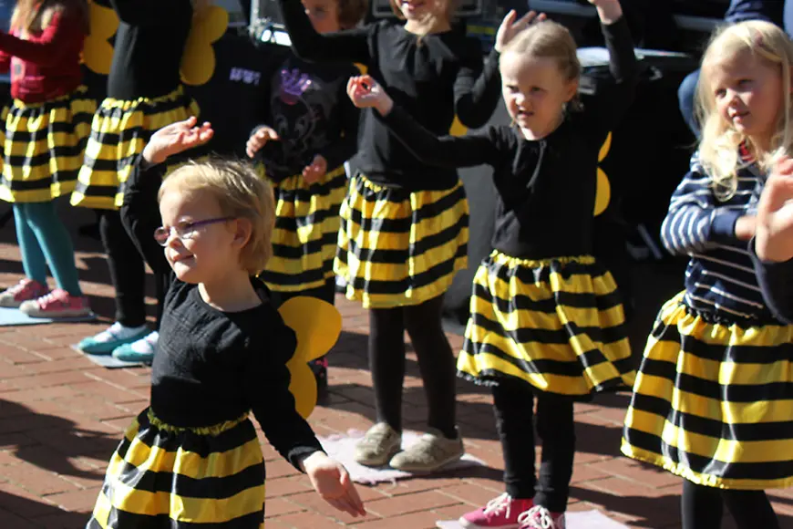 Kinder tanzen als Bienen verkleidet.