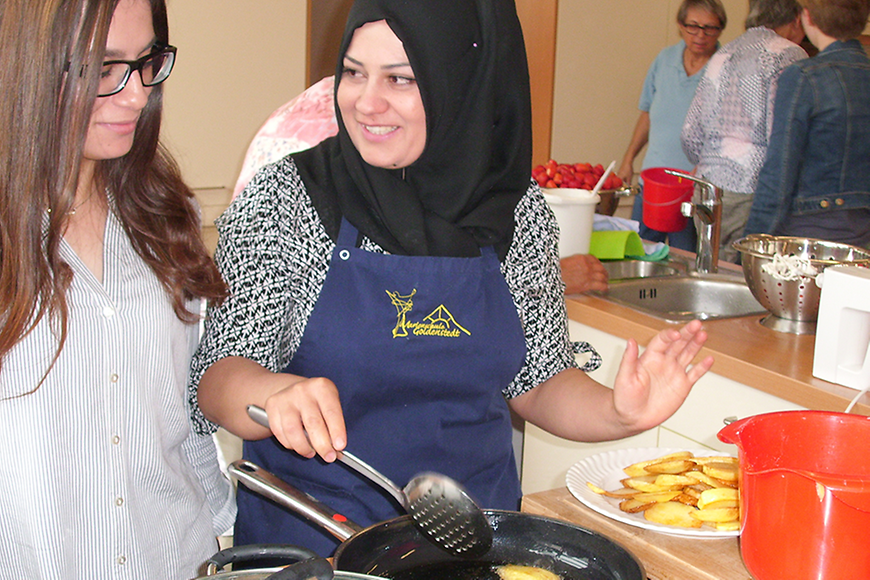 Zwei Frauen kochen, eine Frau trägt Kopftuch