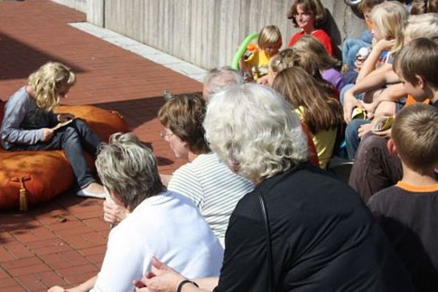 Eine Gruppe die zuhört, während ein Mädchen vorliest.