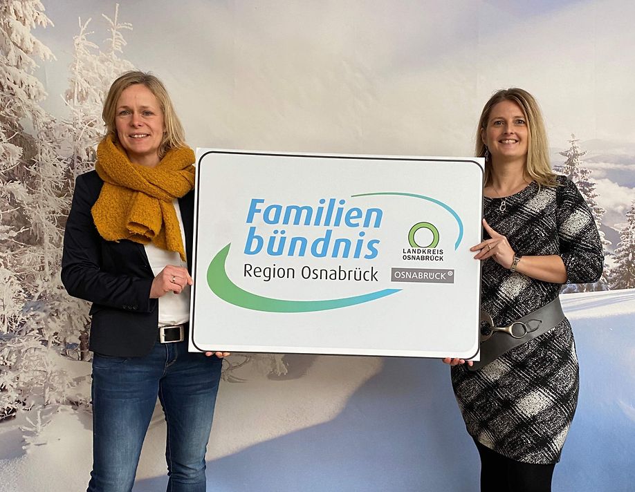 Zwei Vertreterinnen des Familienbündnis in der Region Osnabrück halten ein Schild mit dem Logo des Bündnisses hoch