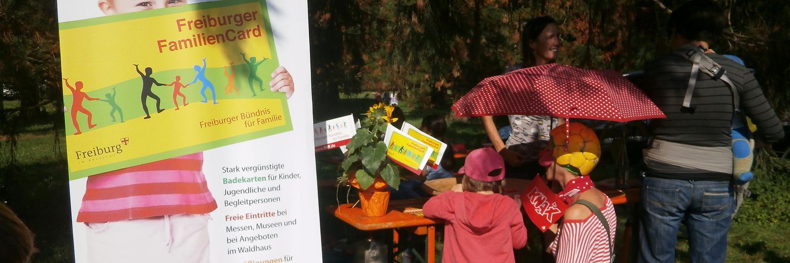 Eine als Clown verkleidete Frau und ein Kind stehen an einem Stand zum Weltkindertag in Freiburg