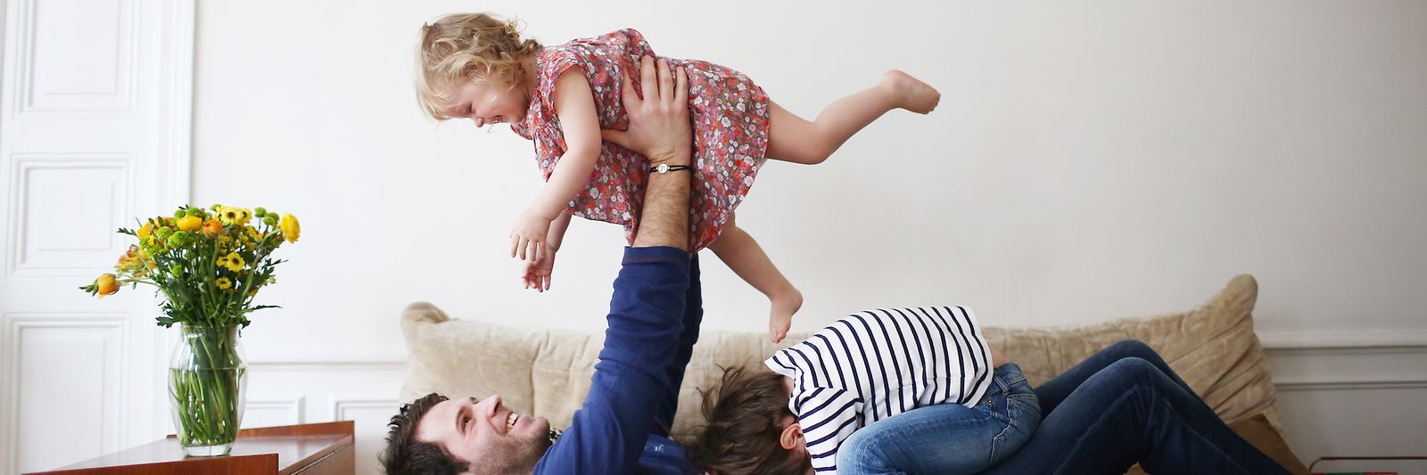 Ein Mann spielt mit zwei Kindern auf einem Sofa.