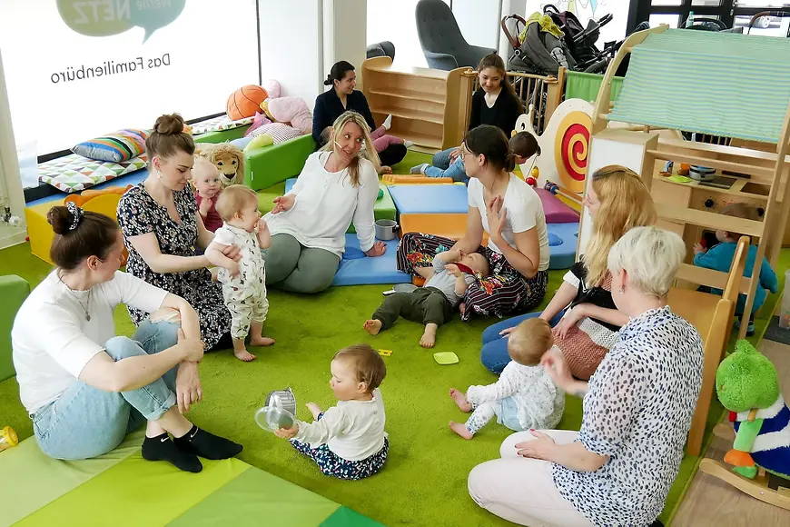 Zu sehen sind auf dem Boden sitzende Mütter mit ihren Babys, die miteinander sprechen.