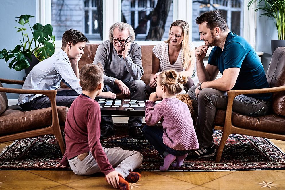 Eine Familie sitzt an einem Couchtisch und spielt Karten.