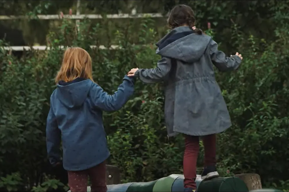 Zwei kleine Kinder halten sich beim Spazieren an den Händen.