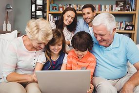 Lachende Kinder, Eltern und Großeltern mit Laptop