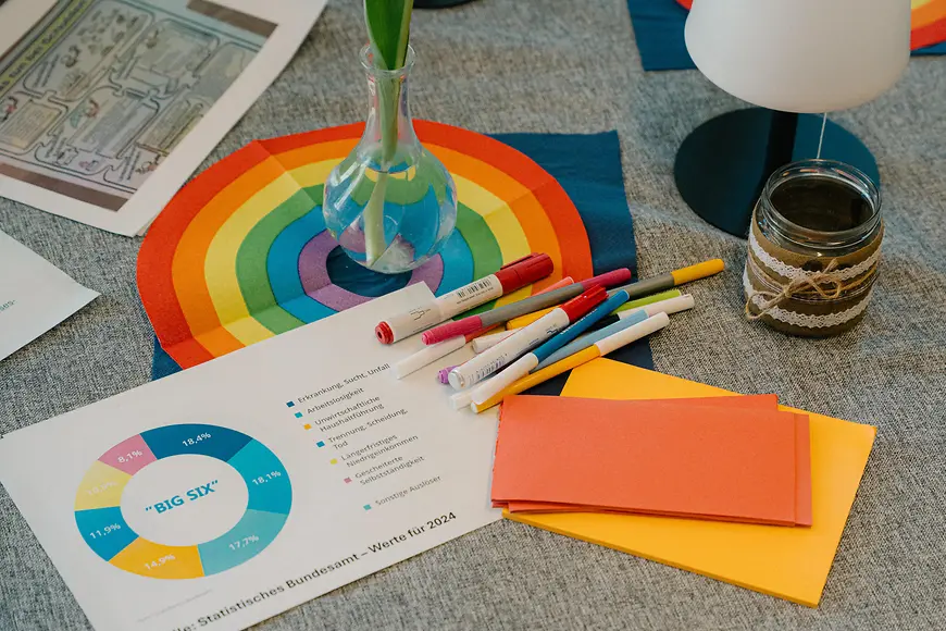 Stifte und buntes Papier liegen auf einem Tisch