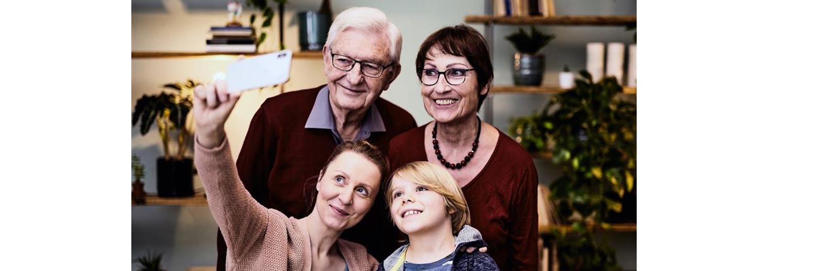 Eine Familie mit Großeltern, Mutter und Kind nimmt ein Selfie auf.