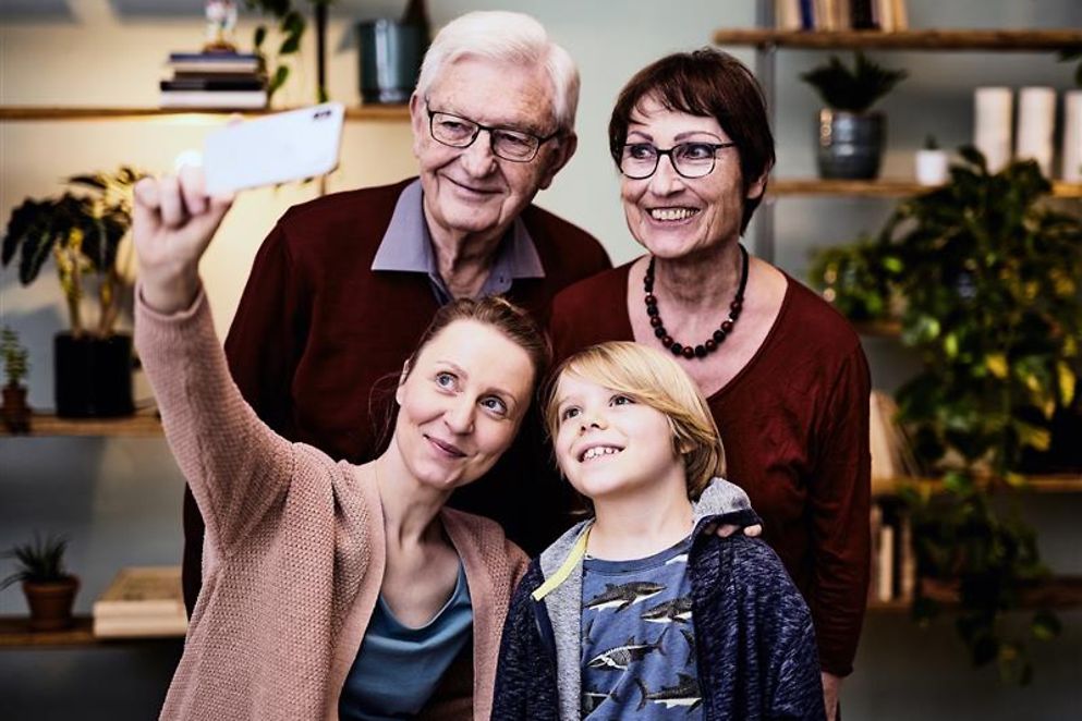 Eine Familie mit Großeltern, Mutter und Kind nimmt ein Selfie auf.