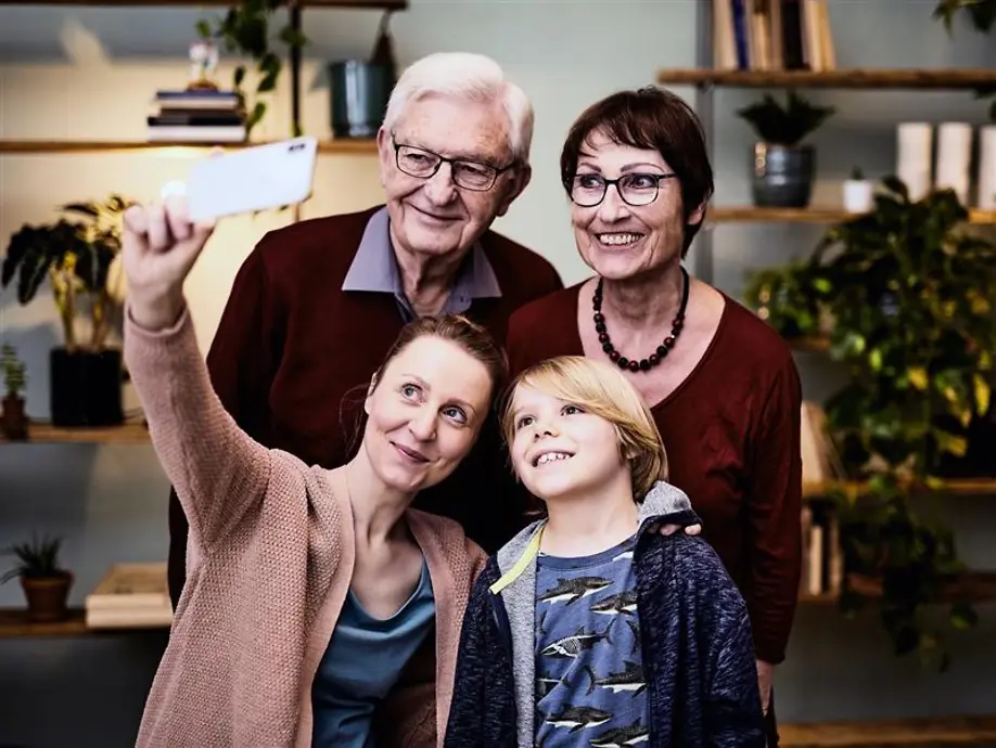 Eine Familie mit Großeltern, Mutter und Kind nimmt ein Selfie auf.
